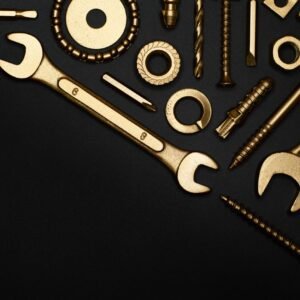 A collection of golden tools arranged in a flat lay on a black surface, perfect for industrial themes.